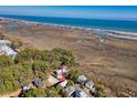 An aerial perspective shows the beautiful home among marshlands near the sandy beach coast at 189 Brown Pelican Loop, Pawleys Island, SC 29585