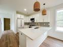 Modern kitchen with white cabinets, updated appliances, an island and gorgeous pendant lights at 189 Brown Pelican Loop, Pawleys Island, SC 29585