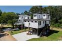 Stylish elevated modern home featuring eye-catching white siding and dark trim at 216 Brown Pelican Loop, Pawleys Island, SC 29585