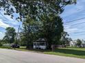 Single story white home nestled beneath the shade of a large tree with a chain link fence and street view at 114 Henry Mcgill St., Marion, SC 29571