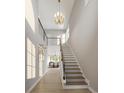Bright hallway with staircase featuring wood treads, modern railing, and a decorative chandelier fixture at 2247 Sand Dunes Dr., Myrtle Beach, SC 29577