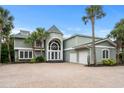 The two-story home has a brick driveway, palm trees, and a grand arched entryway at 8000 Beach Dr., Myrtle Beach, SC 29572
