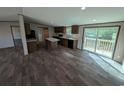 Kitchen with island, dark cabinets, vinyl floors, and sliding glass doors that provide natural lighting at 2500 Newton Rd., Aynor, SC 29511