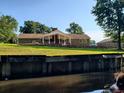 Water view of back of brick home with covered porch on a manicured green lawn at 5864 Crestwood Dr., Myrtle Beach, SC 29578