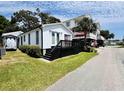 Charming white cottage with a black deck, enhanced by lush landscaping, offers curb appeal at 6001 - 5410 S Kings Hwy., Myrtle Beach, SC 29575