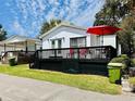 Charming white cottage with a black deck, enhanced by a bright red umbrella, offers curb appeal at 6001 - 5410 S Kings Hwy., Myrtle Beach, SC 29575