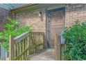 Close-up of a charming front door with wood railings, a storm door, and verdant shrubbery at 305 Resort Dr. # C12, Myrtle Beach, SC 29588