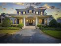 Stunning two-story white brick home with large columns and professionally landscaped front yard at twilight at 9318 Cove Dr., Myrtle Beach, SC 29572