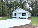 Inviting home featuring a well-kept lawn, and a driveway, all set amidst a lush, green backdrop of trees at 74 Greentown Rd., Georgetown, SC 29440