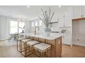 A modern kitchen with an island, light wood floors, and white cabinets next to a dining area at 512 9Th Ave. S, North Myrtle Beach, SC 29582