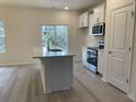 Modern kitchen with island, stainless steel appliances, white cabinets, and natural lighting at 1581 Highway 701 South, Loris, SC 29569