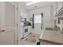 Bright kitchen with white cabinets, stainless steel appliances, tile floor, and blue curtains at 2090 Cross Gate Blvd. # 205, Surfside Beach, SC 29575