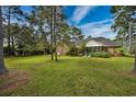 A serene backyard featuring a screened porch, lush green grass and mature trees at 3517 Golf Ave., Little River, SC 29566