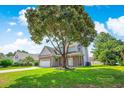 Inviting two-story home with a brick and siding facade and a well-manicured lawn, shaded by a mature tree at 629 Slash Pine Ct., Myrtle Beach, SC 29579