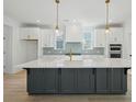 Bright, modern kitchen with a large island, white cabinets, gold hardware, and stainless steel appliances at 1099 Milford Way, Myrtle Beach, SC 29588