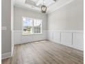 Living room featuring wood floor, large window, wainscoting, decorative ceiling, and elegant chandelier at 205 Waterfall Circle, Little River, SC 29566
