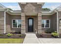 Close-up of a charming brick home entrance, featuring an arched front door, manicured landscaping, and white-framed windows at 297 Waterfall Circle, Little River, SC 29566