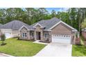 Beautiful brick home with an attached two-car garage and lush green lawn at 309 Waterfall Circle, Little River, SC 29566