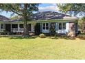 Beautiful brick home showcasing blue shutters, manicured lawn, and a charming covered porch at 1562 Hawthorn Dr., Pawleys Island, SC 29585