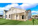 Back exterior featuring a covered patio, sliding glass doors, a spacious backyard, and white siding at 5028 Cambria Ct., Little River, SC 29566