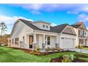 Beautiful home with a covered front porch, stone accents, landscaped yard, and two-car garage at 5028 Cambria Ct., Little River, SC 29566