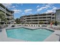Condominium pool with a sun-soaked pool deck and seating area with an airy and open atmosphere at 1101 Possum Trot Rd. # B302, North Myrtle Beach, SC 29582
