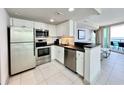 A full kitchen with stainless appliances, white cabinets, and a breakfast bar overlooking the living room at 107 S Ocean Blvd. # 808, Myrtle Beach, SC 29577