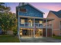 Two-story home with blue siding, a wrap-around porch, and a spacious driveway at dusk at 508 21St Ave. N, North Myrtle Beach, SC 29582