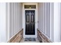 A black front door with glass panels, a 'Welcome' mat, and stone accents along the home's facade at 263 Red Maple Loop, Longs, SC 29568