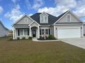 Charming gray home featuring a two-car garage, manicured lawn, and tasteful landscaping, creating an inviting curb appeal at 2327 King Farm Rd., Aynor, SC 29511