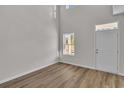 Bright living room featuring wood floors, large windows, tall ceilings, and a white entry door at 794 Nw Palm Frond Way # 48, Calabash, NC 28467
