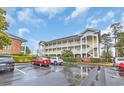 Condo building exterior showcasing a parking area with multiple cars and well-manicured landscaping at 703 Riverwalk Dr. # 304, Myrtle Beach, SC 29579