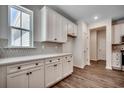 Well-lit kitchen showcasing white cabinets, modern backsplash, wood flooring, and a bright window view at 8667 Farrier Dr., Myrtle Beach, SC 29588