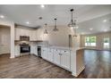 Bright kitchen featuring white cabinets, stainless appliances, wood flooring, and decorative pendant lighting at 8667 Farrier Dr., Myrtle Beach, SC 29588