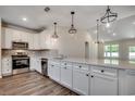 Bright kitchen featuring white cabinets, stainless appliances, wood flooring, and decorative pendant lighting at 8667 Farrier Dr., Myrtle Beach, SC 29588