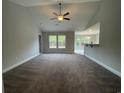 Bright living room featuring neutral walls, carpet floors, a ceiling fan, and seamless access to the kitchen at 910 Padgett Lane, Conway, SC 29526