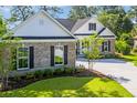 Beautiful home exterior showing the landscaped yard, light colored exterior, and black shutters at 2588 Lake Vista Dr., Little River, SC 29566