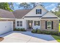 Beautiful home featuring a light exterior, side load garage, dark shutters, and manicured landscaping at 2588 Lake Vista Dr., Little River, SC 29566