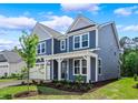 Beautiful two-story home featuring a two-car garage, blue siding, manicured lawn, and a charming covered entrance at 5036 Cambria Ct., Little River, SC 29566