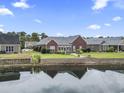 Rear view of brick home with a peaceful pond view and a charming backyard patio at 1066 Brentford Pl., Myrtle Beach, SC 29579