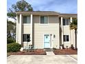 Inviting condo with a light blue door and charming front patio seating area at 951 Plantation Dr. # F1, Little River, SC 29566