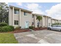 Row of tan townhomes with teal doors and nicely landscaped yards at 951 Plantation Dr. # F1, Little River, SC 29566