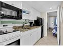 Bright kitchen with white cabinetry, black appliances, and granite countertops at 2001 S Ocean Blvd. # 1506, Myrtle Beach, SC 29577
