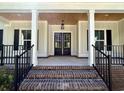 Covered front porch with wood ceiling, black railings and a view of the front door at 909 Grimes St., Georgetown, SC 29440