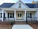 Inviting front porch with brick stairs, black railings, and a stylish wood ceiling at 909 Grimes St., Georgetown, SC 29440