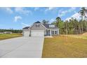 New home with a two-car garage, gray siding, and a well-manicured lawn in a suburban neighborhood at 240 Palmetto Sand Loop, Conway, SC 29527