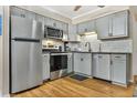 Modern kitchen with stainless steel appliances, gray cabinets, and stylish backsplash and hardwood floors at 6000 N Ocean Blvd. # 214, North Myrtle Beach, SC 29582