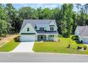 Charming two-story home featuring a covered porch, black metal roof, attached garage, and well-manicured lawn at 604 Mccown Dr., Conway, SC 29526