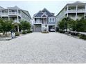 Coastal home featuring a spacious gravel driveway, ground-level garage, and a charming front porch at 253 W Second Ave. S, Ocean Isle Beach, NC 28469