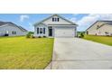 Charming exterior of a light blue home featuring a two-car garage, black shutters, and a manicured lawn at 1044 Jase Dr., Longs, SC 29568
